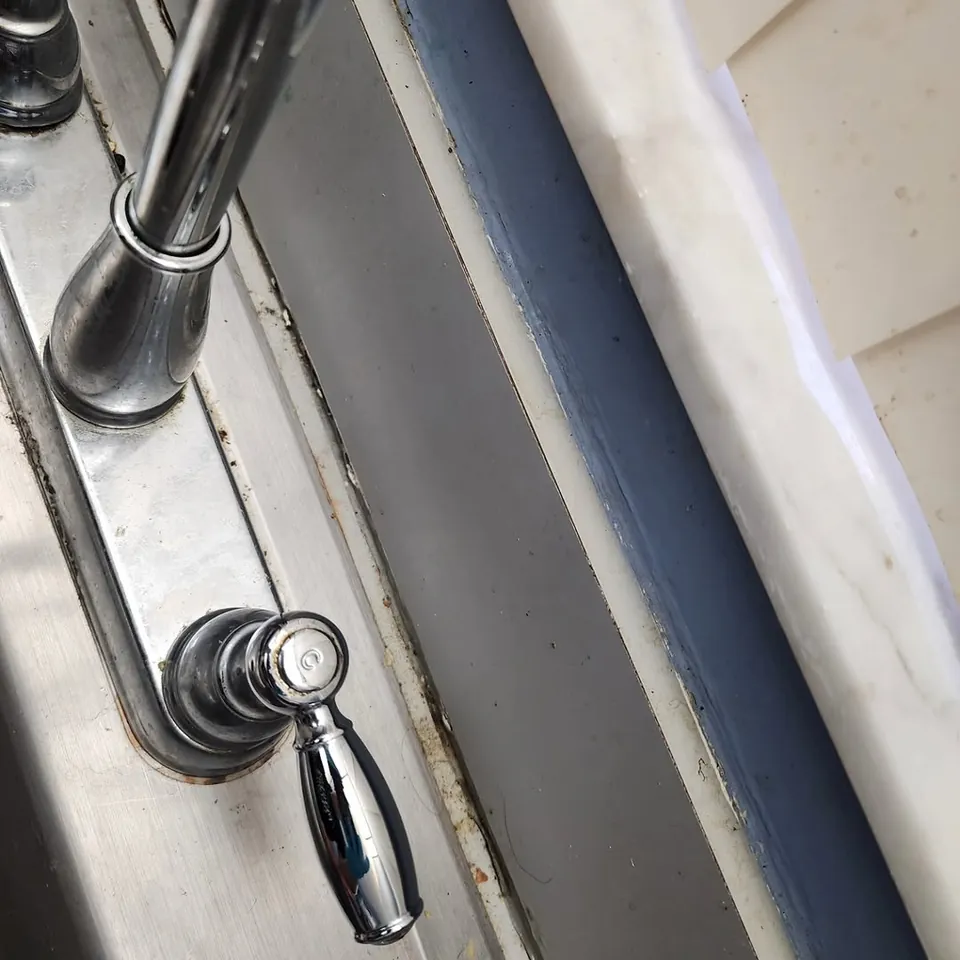 Kitchen faucet before cleaning, with grime built up around the base